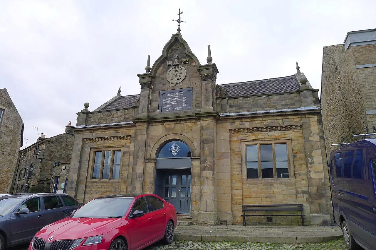 Longnor Market Hall beside parked cars in the village square