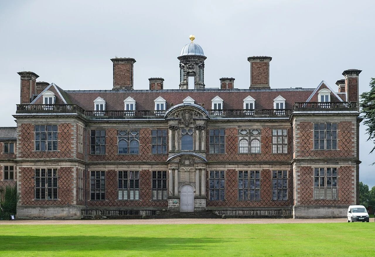Sudbury Hall’s brick facade and white window frames above a lawn