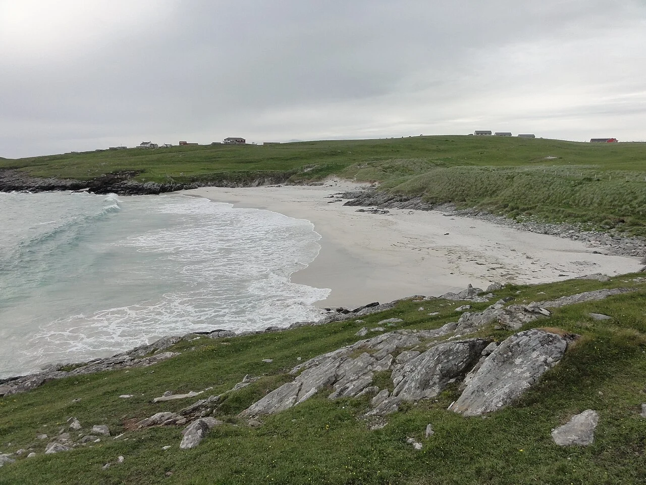 The sandy curve of Meal Beach beneath a grassy bank