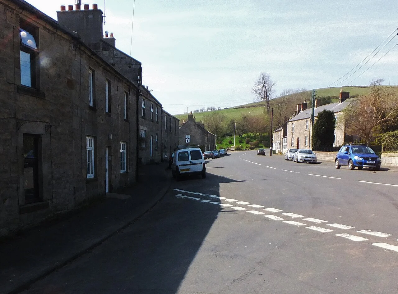 Stone buildings and parked cars along a public street in Glanton